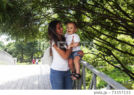 young pretty brunette mother with little cute boy walking in park happy smiling, lifestyle people concept 73357133