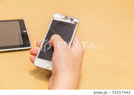 割れたスマホを操作する男性の手元 割れたスマホを操作する男性の手元 73357442