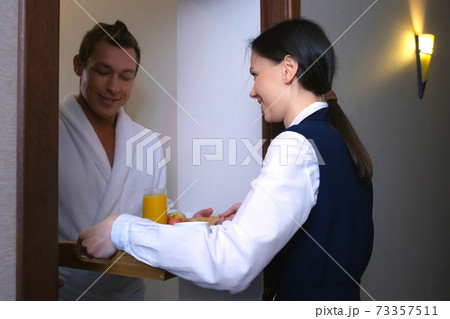 Woman hotel worker maid is carrying a breakfast tray to the guest's room. Woman hotel worker maid is carrying a breakfast tray to the guest's room. 73357511