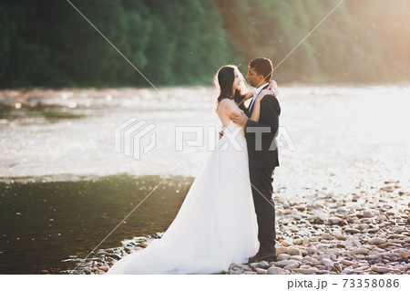 Wedding couple, groom and bride hugging, outdoor near river Wedding couple, groom and bride hugging, outdoor near river 73358086