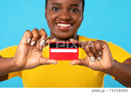 Black Lady Showing Credit Card To Camera Over Blue Background 73358260