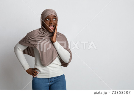 Shocking Offer. Surprised black islamic lady in hijab touching face in excitement Shocking Offer. Surprised black islamic lady in hijab touching face in excitement 73358507