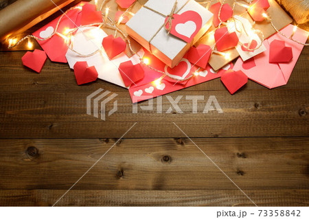 Love, Valentine's, women's day, romantic design from gifts, love letters, colored and wrapped in craft paper, tied with twine with bows, labels, hearts, lights on wooden boards background Love, Valentine's, women's day, romantic design from gifts, love letters, colored and wrapped in craft paper, tied with twine with bows, labels, hearts, lights on wooden boards background 73358842