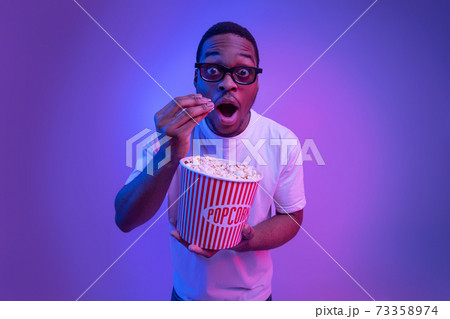 Surprised African Man In 3d Glasses With Popcorn In Cinema, Neon Lighting Surprised African Man In 3d Glasses With Popcorn In Cinema, Neon Lighting 73358974
