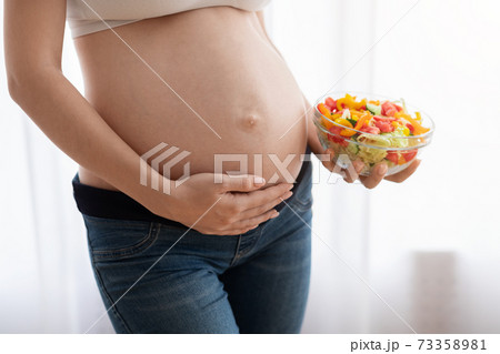 Nutrition For Healthy Pregnancy. Pregnant Woman Holding Vegetable Salad Bowl Near Belly 73358981