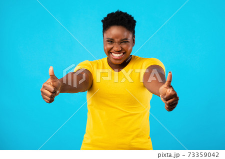 Plus-Size Black Woman Gesturing Thumbs-Up With Both Hands, Blue Background 73359042