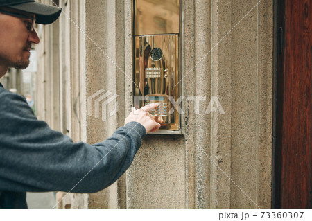 Man presses a doorphone button 73360307