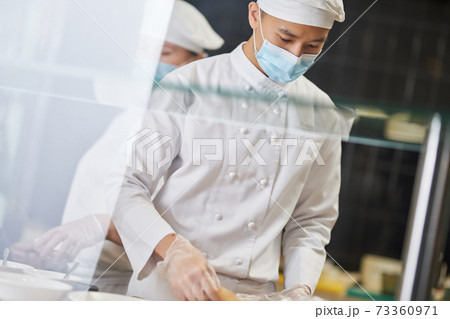 Concentrated chef looking down while cooking new meal Concentrated chef looking down while cooking new meal 73360971