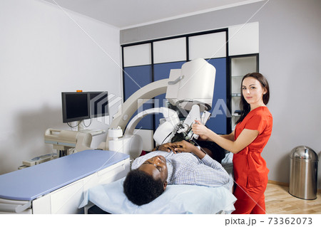 Treatment of urethral stones by non-invasive Extracorporeal Shock Wave Lithotripsy. Pleasant female doctor providing the ultrasonic lithotripsy for her male African patient in modern clinic 73362073