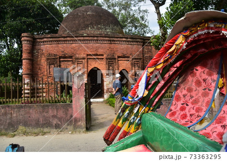 バングラデシュのダッカのショナルガオ　歴史的なゴアルディ・モスジットと停車中のリキシャと観光する男性 73363295