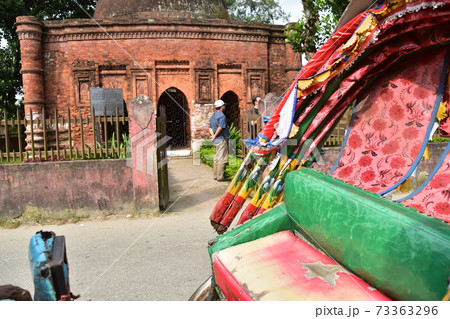 バングラデシュのダッカのショナルガオ　歴史的なゴアルディ・モスジットと停車中のリキシャと観光する男性 73363296