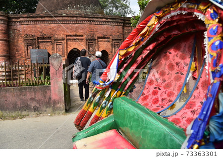 バングラデシュのダッカのショナルガオ　歴史的なゴアルディ・モスジットと停車中のリキシャと観光する男性 73363301