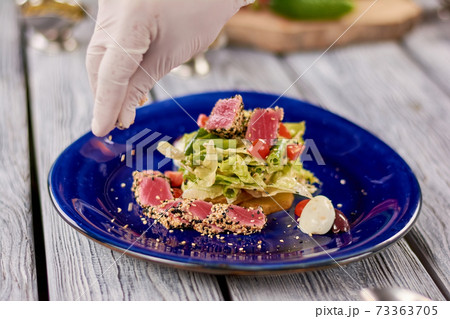 Chef hands sprinkling sesame on salad with tuna. Chef hands sprinkling sesame on salad with tuna. 73363705