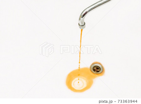Rusty or dirty water flows from a tap into a sink or bathtub 73363944