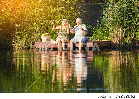 Senior couple sitting near water. Senior couple sitting near water. 73363962