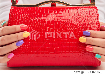 Red lacquered handbag in female hands. Red lacquered handbag in female hands. 73364076