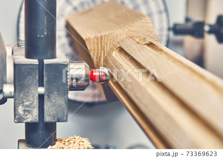 Turning wooden stair balusters. Wood stair balusters manufacturing process on a turning lathe with milling cutter Turning wooden stair balusters. Wood stair balusters manufacturing process on a turning lathe with milling cutter 73369623
