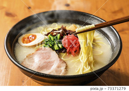箸で持ち上げたとんこつラーメン 73371279