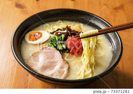 箸で持ち上げたとんこつラーメン 73371281
