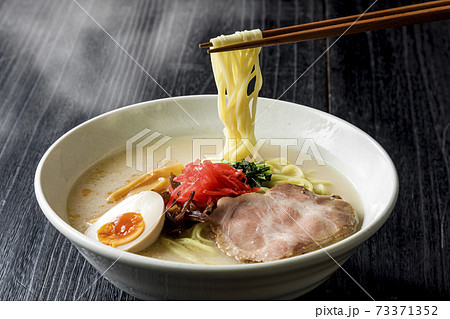 箸で持ち上げた豚骨ラーメン 73371352