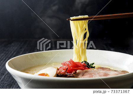 箸で持ち上げた豚骨ラーメン 73371367