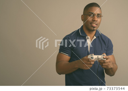 Young handsome African man wearing blue polo shirt against gray background Young handsome African man wearing blue polo shirt against gray background 73373544