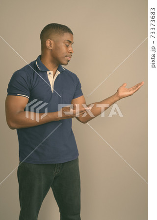 Young handsome African man wearing blue polo shirt against gray background 73373683