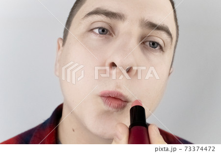 Close-up of a man painting his lips. The concept of protecting the rights of the LGBT community, a clear manifestation of homosexuality and the manifestation of female qualities in men. 73374472