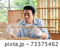 Man blowing sawdust out of timber wood in carpentry workshop. 73375462