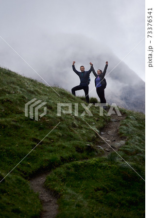 Happy young couple standing on grassy hill. 73376541