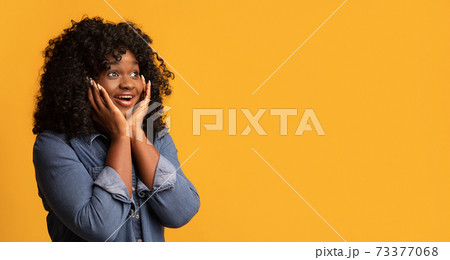 Amazed black woman looking at copy space for advertisement Amazed black woman looking at copy space for advertisement 73377068
