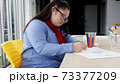 Asian girl with Down's syndrome drawing picture in art class. Concept disabled kid learning. 73377209