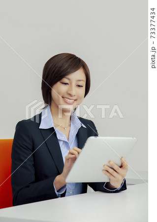 タブレットPCを笑顔で操作するビジネスウーマン タブレットPCを笑顔で操作するビジネスウーマン 73377434