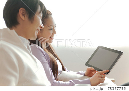ソファに座ってタブレットPCの画面を見る夫婦 ソファに座ってタブレットPCの画面を見る夫婦 73377756
