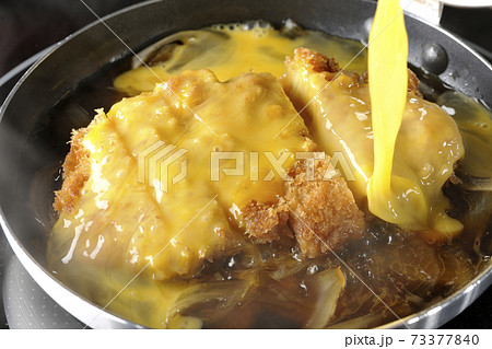 IHクッキングヒーターに対応している親子鍋でカツと玉ねぎを煮て卵でとじる調理シーン 73377840