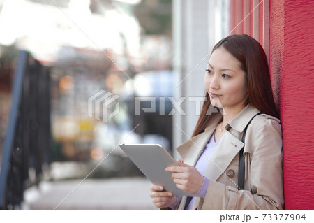 街中でタブレットPCを持つ女性 73377904