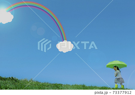 グリーンの傘をさして歩く女の子 青空に虹と雲 グリーンの傘をさして歩く女の子 青空に虹と雲 73377912