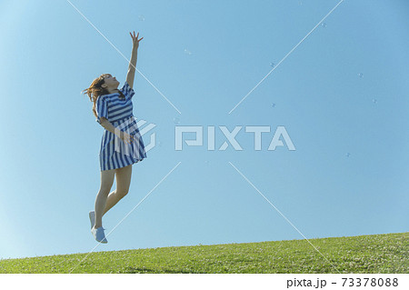 草原をジャンプする女性の写真素材
