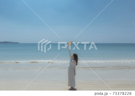 波打ち際で麦わら帽子をかざす女性 波打ち際で麦わら帽子をかざす女性 73378226