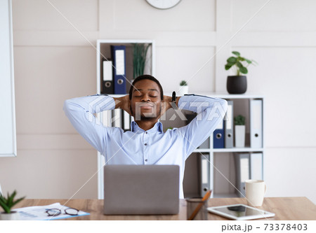 Satisfied african american businessman relaxing on his chair 73378403