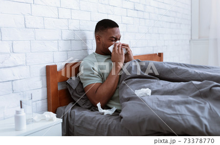 Sick Man Blowing Nose In Tissue Lying In Bed Indoor 73378770