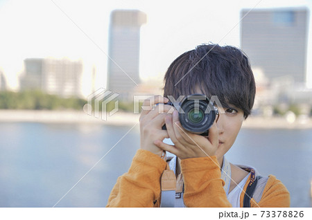 カメラを構える女性と夕暮れのお台場海浜公園 73378826