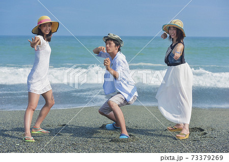 海辺でポーズをとる若者3人の写真素材