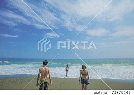 海辺の若者3人の後ろ姿の写真素材