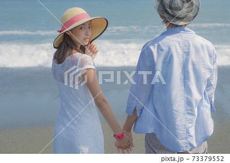 海辺で手をつなぐカップルの後ろ姿の写真素材
