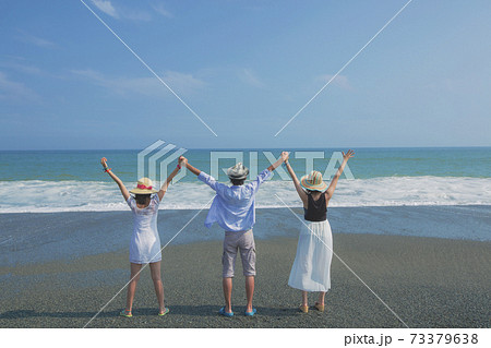 海辺でポーズをとる若者3人の後ろ姿の写真素材