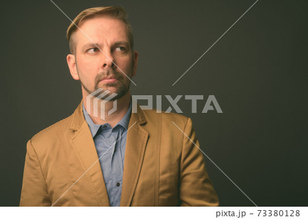 Blond bearded businessman with goatee against gray background Blond bearded businessman with goatee against gray background 73380128