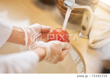 Chef washing a fresh tomato in warm water 73382556