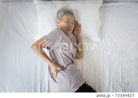 Asian senior woman suffering from backache,sore waist while sleep,unhappy old elderly feeling discomfort pain in her back muscles caused by bad posture or uncomfortable mattress during rest on her bed Asian senior woman suffering from backache,sore waist while sleep,unhappy old elderly feeling discomfort pain in her back muscles caused by bad posture or uncomfortable mattress during rest on her bed 73384827