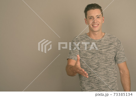 Young handsome man wearing gray shirt against gray background Young handsome man wearing gray shirt against gray background 73385134